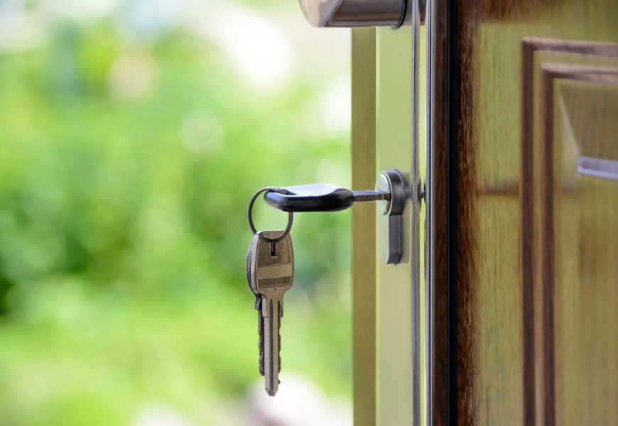 Key inserted in door lock against a blurred green background, symbolizing security and real estate.