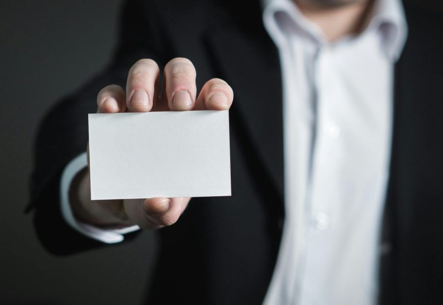 A man in a suit presenting a blank business card for corporate usage.